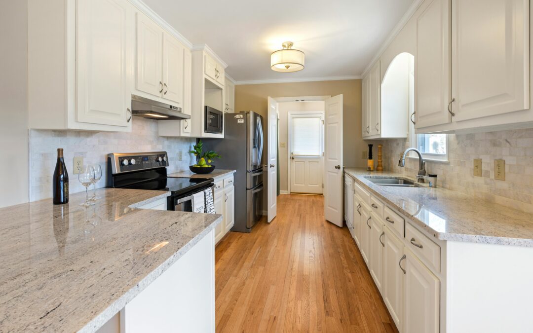 A modern kitchen with sleek white cabinets, a large central island, stainless steel appliances, and stylish pendant lighting